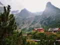 Słowackie Tatry: schroniska nad jeziorem, otoczone zielenią i majestatycznymi szczytami, z mgłą unoszącą się w tle.