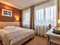 Przytulny pokój hotelowy w Białymstoku z wygodnym łóżkiem, biurkiem i telewizorem.