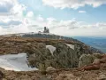 Budynek na szczycie góry w Karkonoszach, z widokiem na dolinę i chmury.