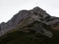 Grupa turystów podąża szlakiem na Giewont. W oddali widać charakterystyczny krzyż na szczycie.