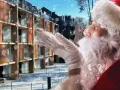 Śnieżynki tańczą wokół Świętego Mikołaja dmuchającego śniegiem na nowoczesny hotel. Czas na mikołajki w hotelu!
