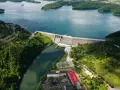 Zapora Solina z lotu ptaka, otoczona zielonymi wzgórzami i błękitną wodą. Planujesz wycieczkę? Sprawdź zapora Solina bilety!