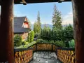 Drewniany dom z widokiem na góry, otoczony lasem. Widok z tarasu z rzeźbioną balustradą, idealne miejsce na relaks w stylu Gubałówka Zakopane.