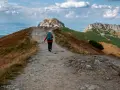 Wędrowiec idzie ścieżką ku czerwonym wierchom z kir. W tle rozciąga się malownicza panorama Tatr.
