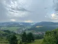 Widok na dolinę z wioską i wzgórzami w tle, chmury nad przełęczą pod Tokarnią.