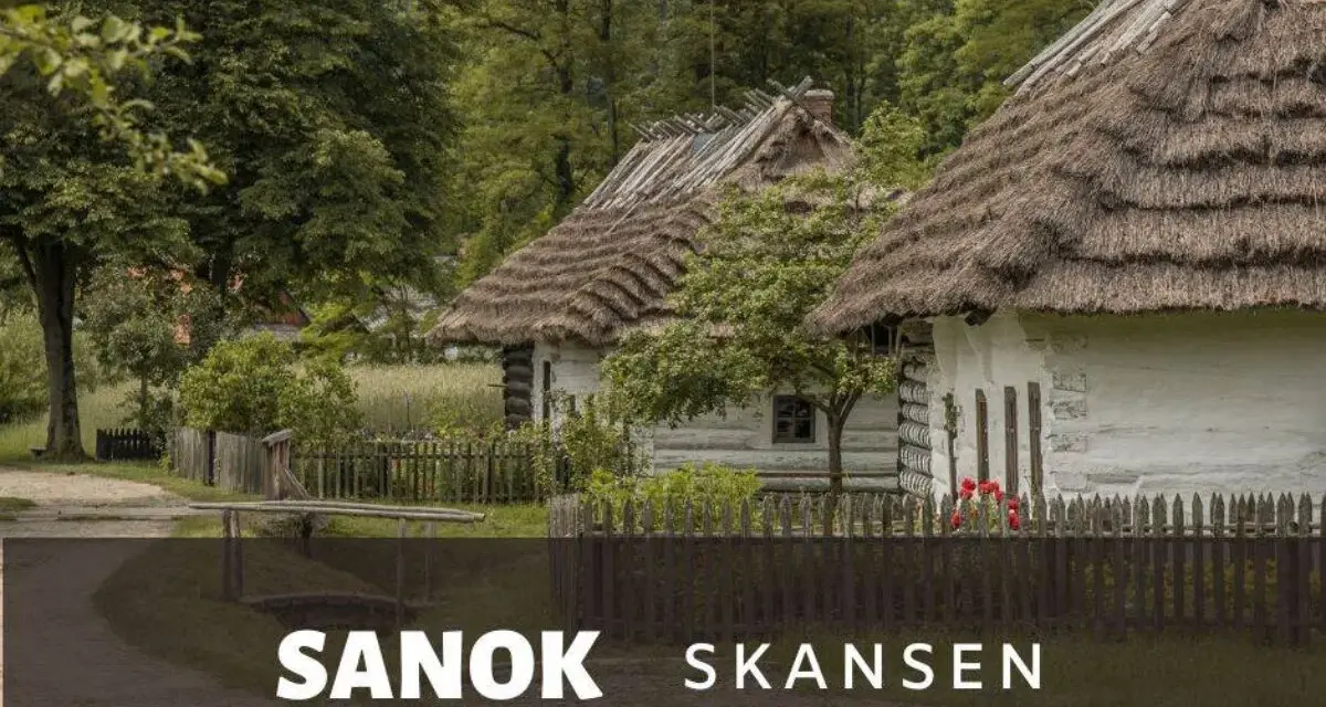 Skansen Sanok: tradycyjne chaty kryte strzechą, zielone drzewa i płot. Sprawdź cennik i zaplanuj wizytę!