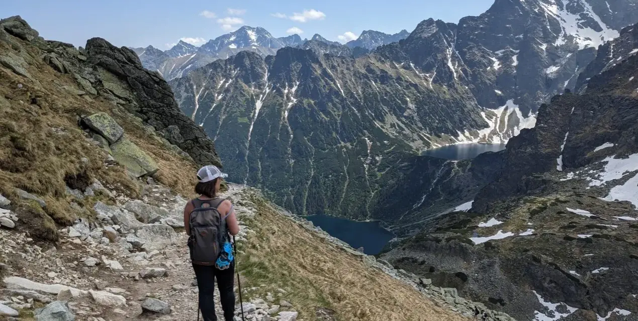 Trasa na Szpiglasowy Wierch. Turystka z plecakiem idzie kamienistym szlakiem, podziwiając widok na Tatry i Morskie Oko.