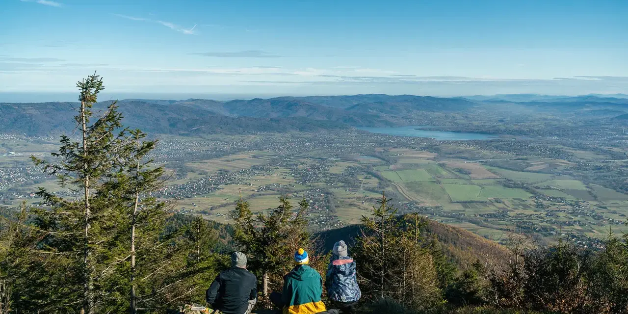 Rodzina podziwia widok ze Skrzycznego. Dziecko z rodzicami cieszy się panoramą Beskidów.