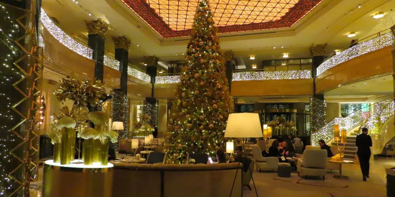 Elegancka wigilia w hotelu. Ogromna choinka, złote dekoracje i migoczące światełka tworzą magiczną atmosferę.