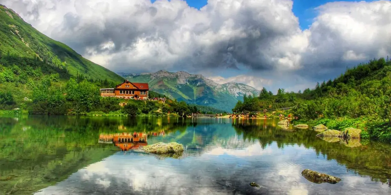 Piękne tatry słowackie z dziećmi, schronisko nad jeziorem, góry i chmury odbijające się w wodzie.