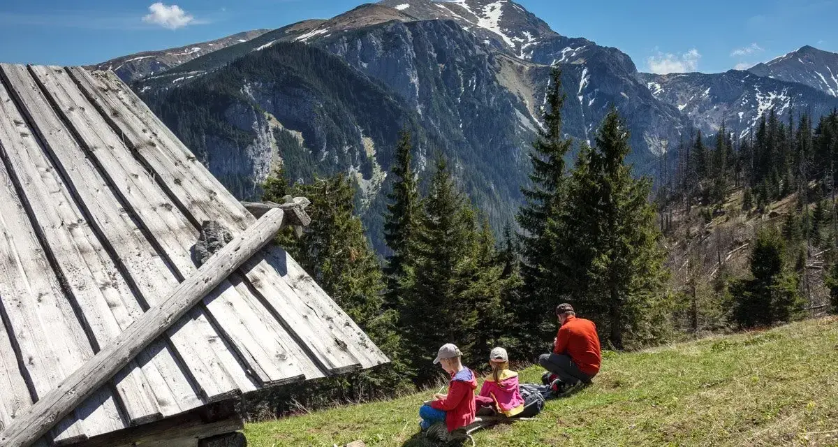 Rodzina odpoczywa przy szałasie, podziwiając Tatry. Idealne tatry atrakcje dla leniwych, gdzie można usiąść i cieszyć się widokiem.