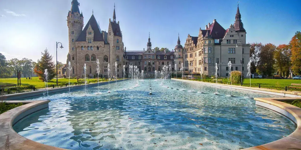 Zamek Książ z fontannami, jedna z głównych moszna atrakcje. Piękny dzień, błękitne niebo i woda tworzą magiczny widok.