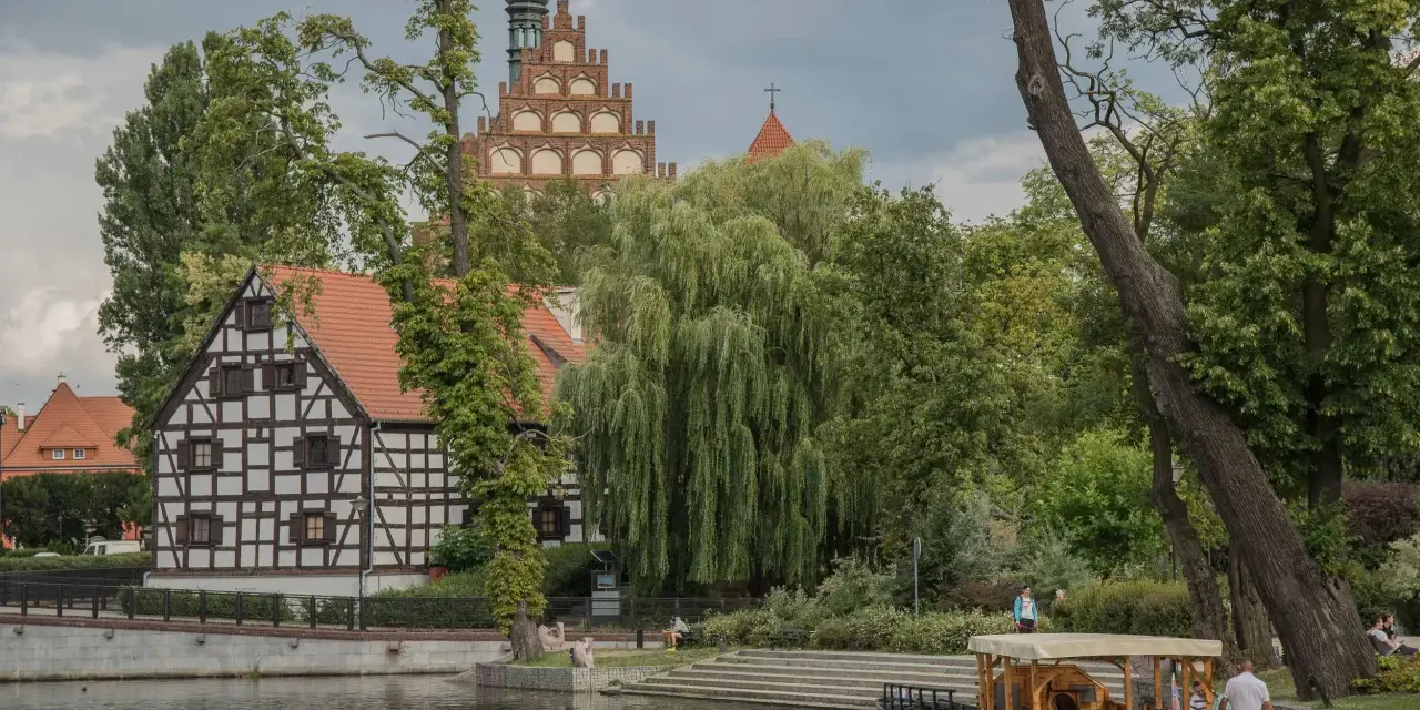 Malownicze pomorskie atrakcje na weekend: zabytkowa zabudowa, rzeka i łódź. Idealne miejsce na relaks.