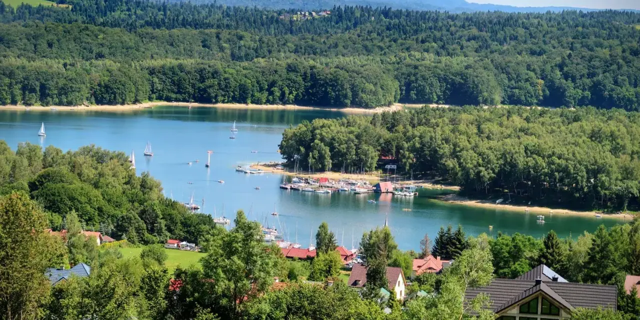 Malownicze Bieszczady z dziećmi: jezioro, żaglówki, las i domki letniskowe. Idealne miejsce na wakacje.