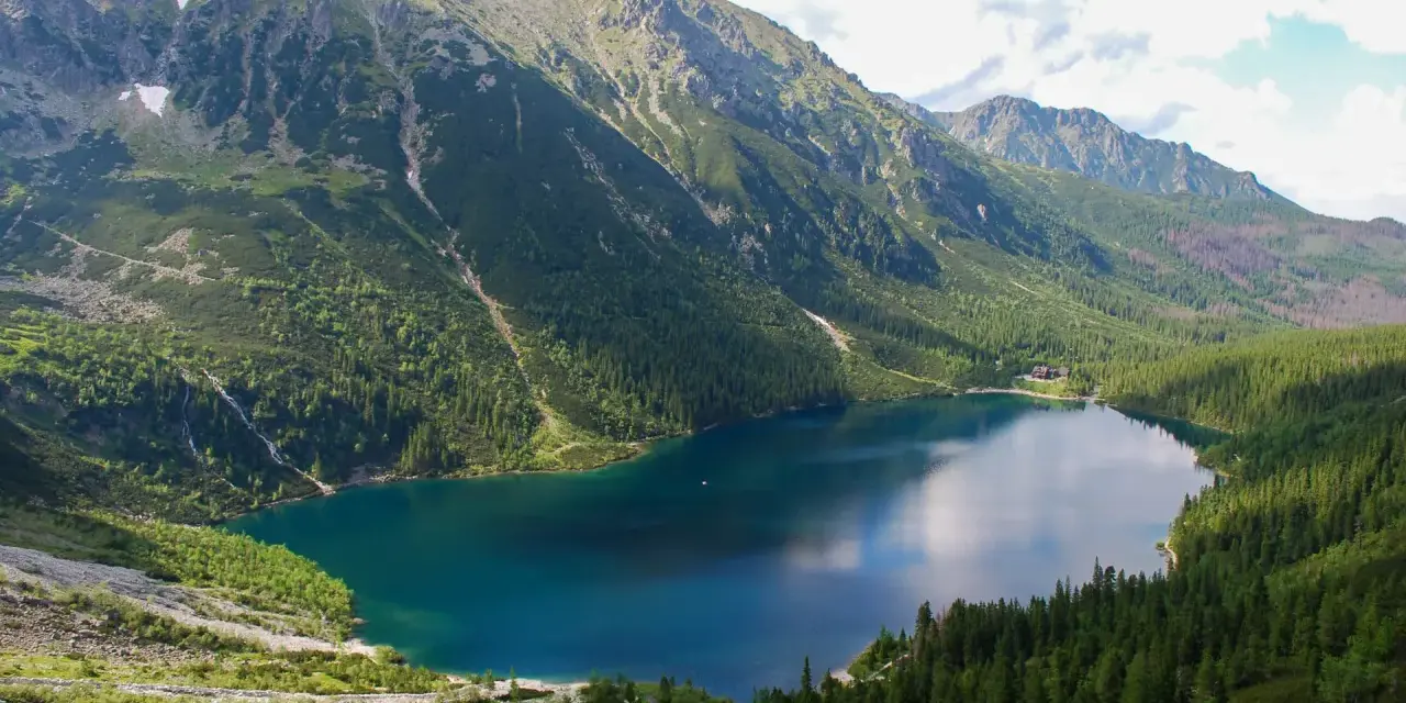 Morskie Oko, największe jezioro w Tatrach, otoczone zielonymi lasami i skalistymi szczytami.