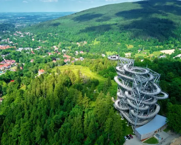 Widok na wieżę widokową w otoczeniu lasów i miasteczka. Idealne miejsce, gdzie w góry można wybrać się na spacer i podziwiać panoramę.