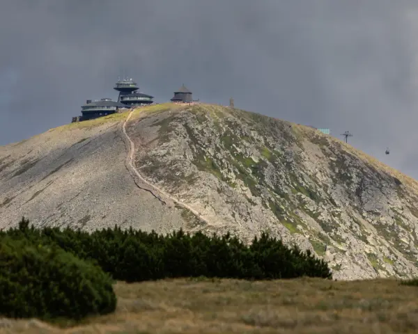 Schronisko i obserwatorium na szczycie w Karkonoszach, z widoczną kolejką linową i kamienistym zboczem.