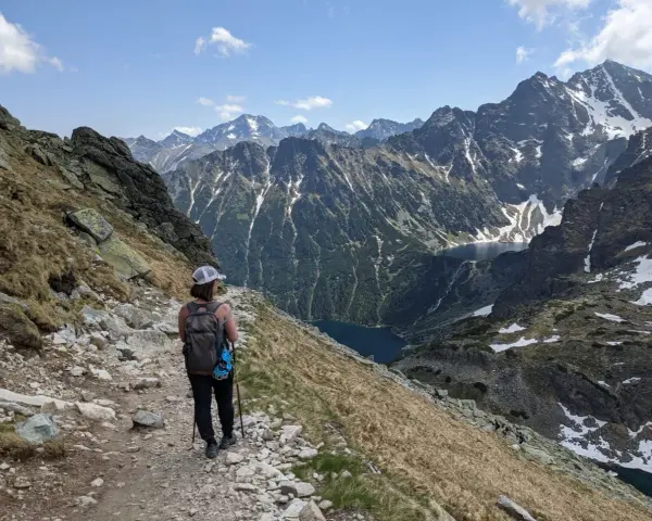 Trasa na Szpiglasowy Wierch. Turystka z plecakiem idzie kamienistym szlakiem, podziwiając widok na Tatry i Morskie Oko.