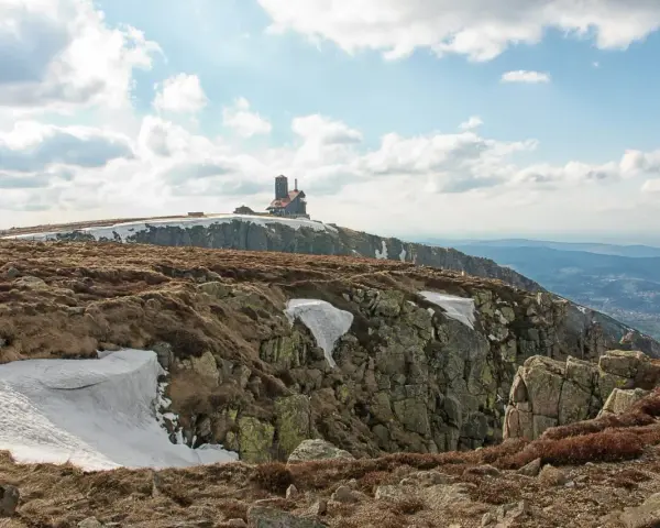 Budynek na szczycie góry w Karkonoszach, z widokiem na dolinę i chmury.