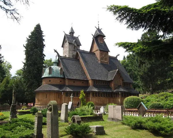 Drewniana świątynia Wang w Karpaczu, otoczona cmentarzem i drzewami. Ciekawostki o jej budowie i historii przyciągają turystów.