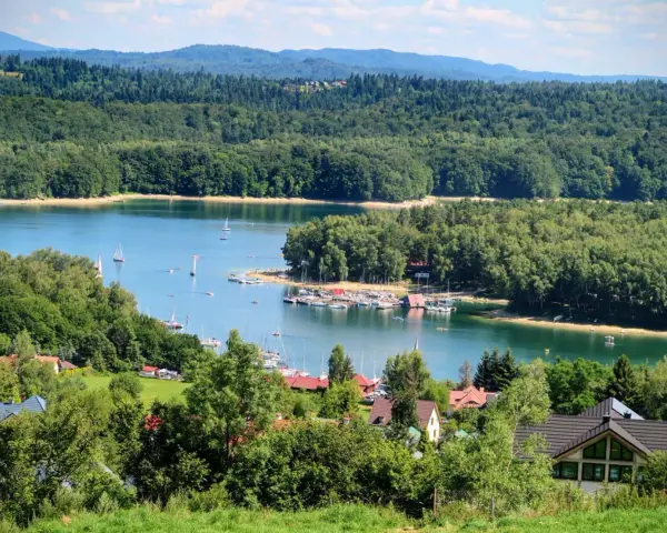 Malownicze Bieszczady z dziećmi: jezioro, żaglówki, las i domki letniskowe. Idealne miejsce na wakacje.