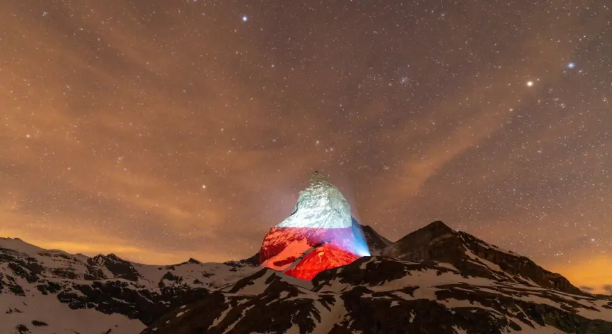 Górski szczyt, niczym polski Matterhorn, rozświetlony nocą polskimi barwami pod rozgwieżdżonym niebem.