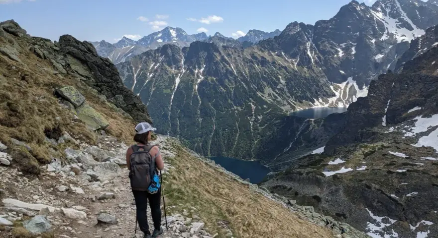 Trasa na Szpiglasowy Wierch. Turystka z plecakiem idzie kamienistym szlakiem, podziwiając widok na Tatry i Morskie Oko.