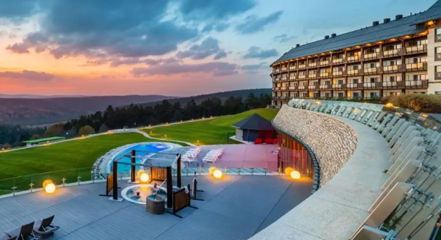 Luksusowy hotel z basenem i jacuzzi na tle zachodzącego słońca. Jeden z największych hoteli w Polsce oferuje relaks w malowniczej scenerii.