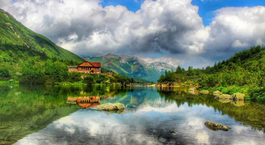Piękne tatry słowackie z dziećmi, schronisko nad jeziorem, góry i chmury odbijające się w wodzie.