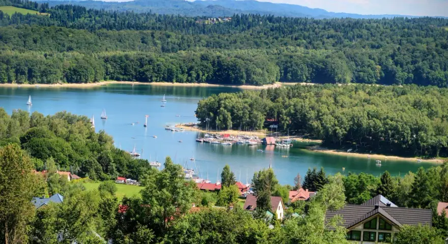 Malownicze Bieszczady nad Jeziorem Solińskim. Woda lśni, żaglówki kołyszą się, a lasy otulają brzeg.