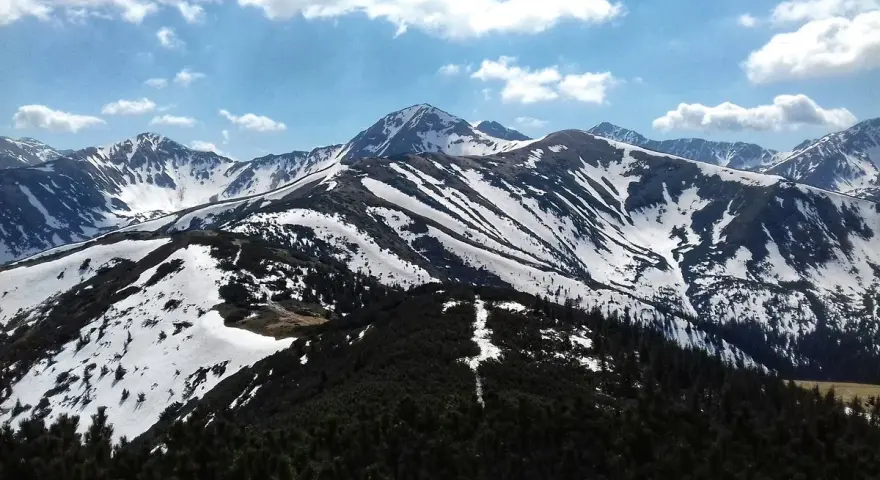 Majestatyczne Tatry w kwietniu, pokryte śniegiem szczyty i zielone lasy.