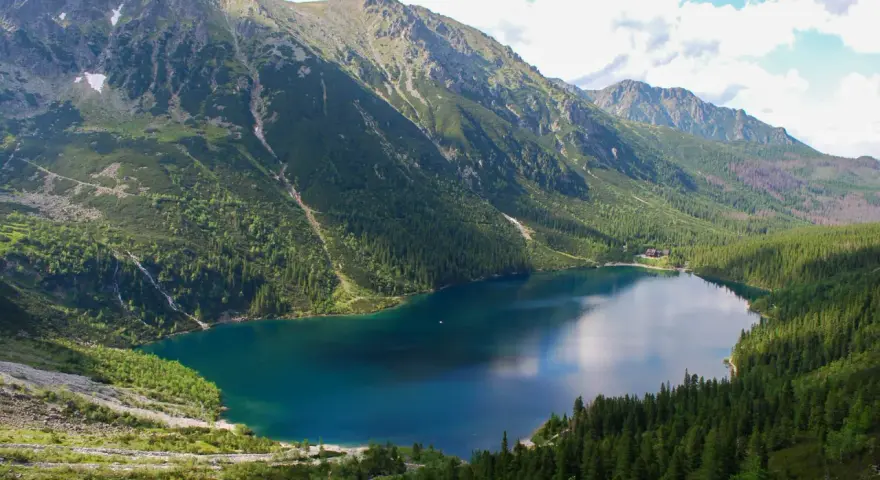 Morskie Oko, największe jezioro w Tatrach, otoczone zielonymi lasami i skalistymi szczytami.