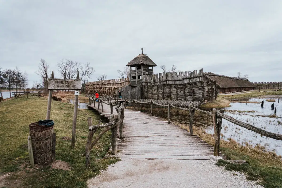 Drewniany most prowadzi do grodu z wieżą strażniczą. To fragment szlaku piastowskiego, gdzie można poczuć ducha minionych wieków.