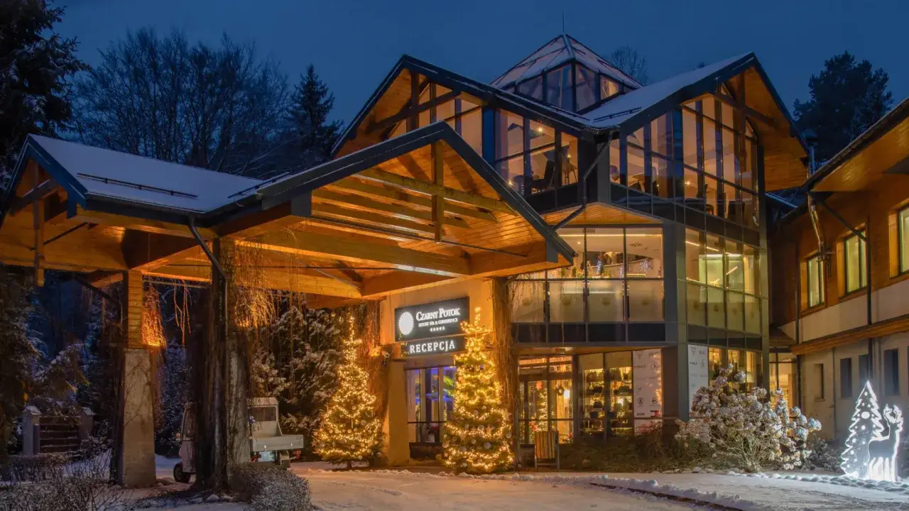 Elegancki hotel o zmierzchu, ozdobiony świątecznymi lampkami. Idealne miejsce na pobyt z kolacją wigilijną.