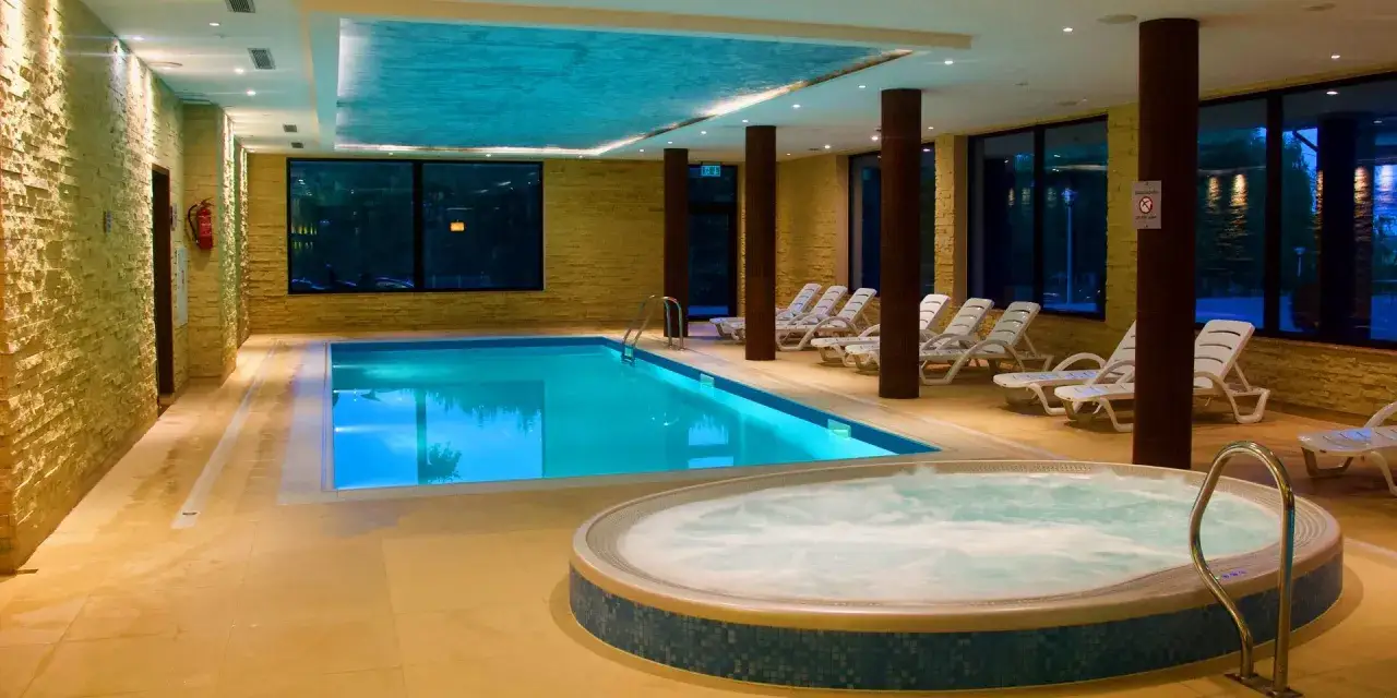 Relaks w Mikołajki Resort Spa: basen z błękitną wodą, jacuzzi i leżaki czekają na gości.