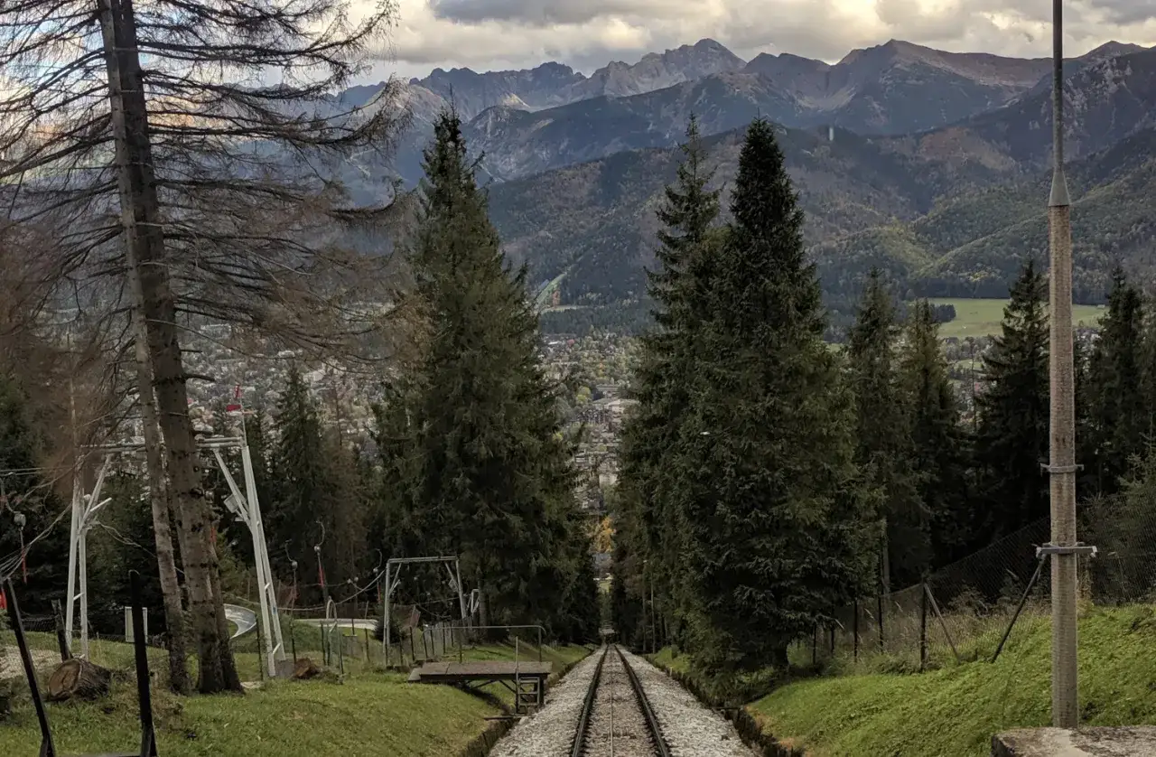 Tory kolejki na Gubałówkę w Zakopanem prowadzą w dół, ku miastu, z którego roztacza się widok na majestatyczne Tatry.