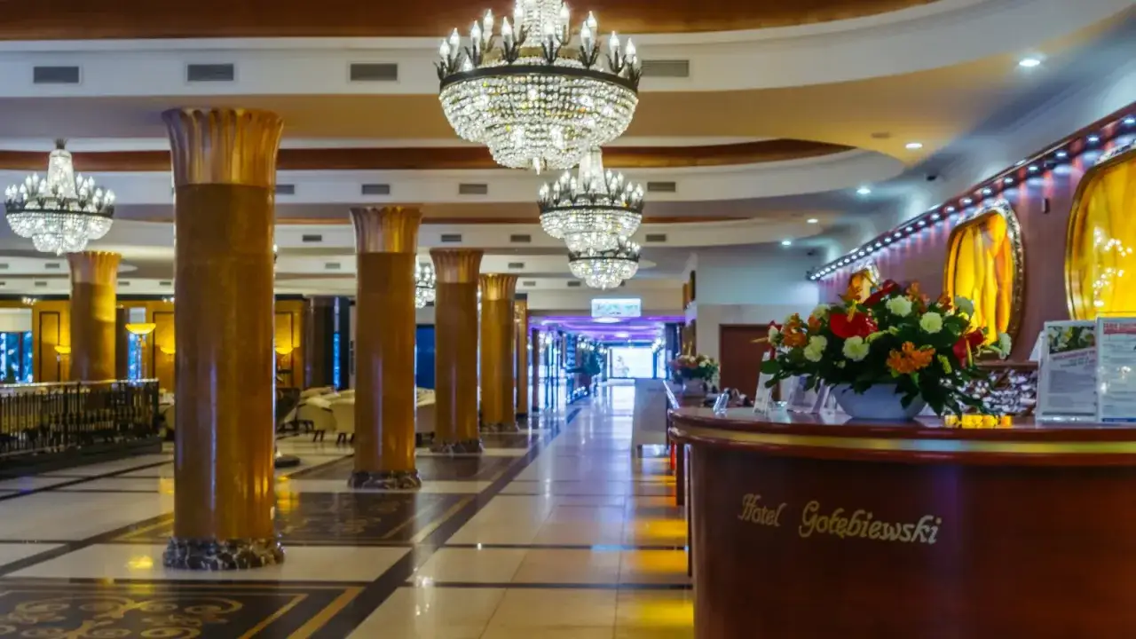 Eleganckie wnętrze hotelu Gołębiewski z kryształowymi żyrandolami i złotymi kolumnami. Czy to właśnie tutaj znajduje się najstarszy hotel Gołębiewski?