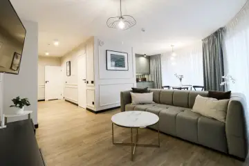 Nowoczesny apartament suite, z wygodną kanapą, stolikiem kawowym i widokiem na kuchnię.