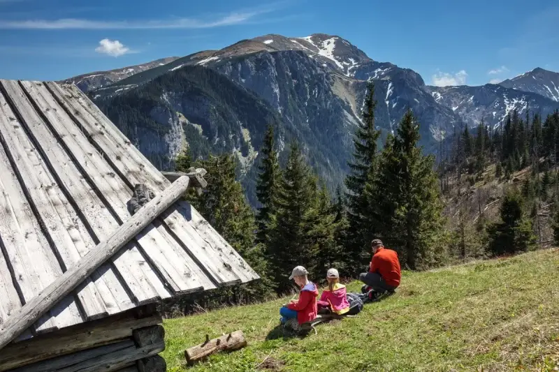 Rodzina odpoczywa przy szałasie, podziwiając Tatry. Idealne tatry atrakcje dla leniwych, gdzie można usiąść i cieszyć się widokiem.